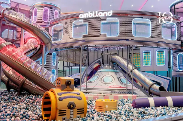 Основная игровая зона в ambi.land в ТРЦ Океания: открытая игровая площадка с неоновой подсветкой, высокими стальными горками, воронкой и сухим бассейном.