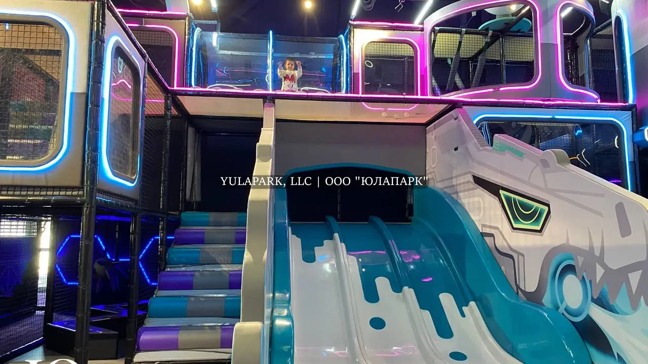 Прозрачный стеклянный мост, горки в виде волны в белом и голубом цветах в новом лабиринте с подсветкой в стиле города будущего.