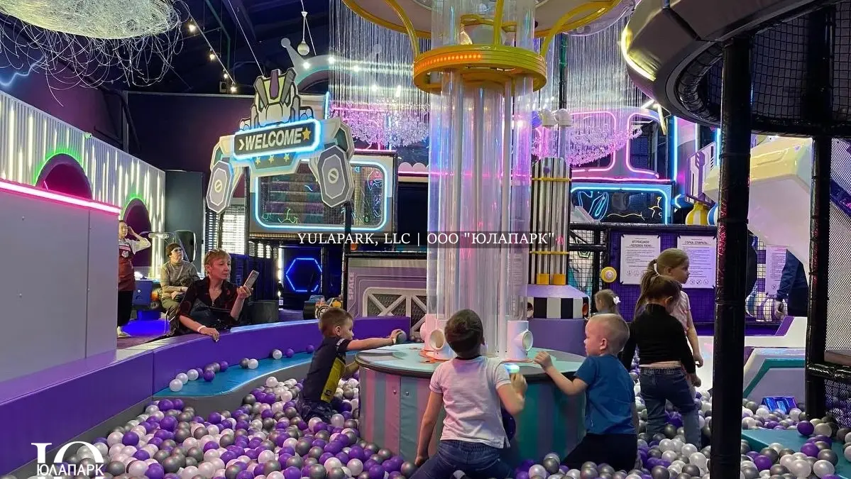 Фиолетовые и белые шарики в сухом бассейне, горка в виде змея и динозавтра, сухой фонтан с шарами и большой детский лабиринт в развлекательном центре для детей.