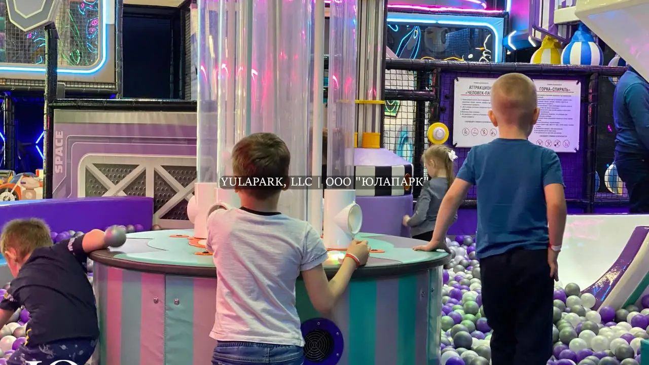 Фиолетовые и белые шарики в сухом бассейне, горка в виде змея и динозавтра, сухой фонтан с шарами и большой детский лабиринт в развлекательном центре для детей.