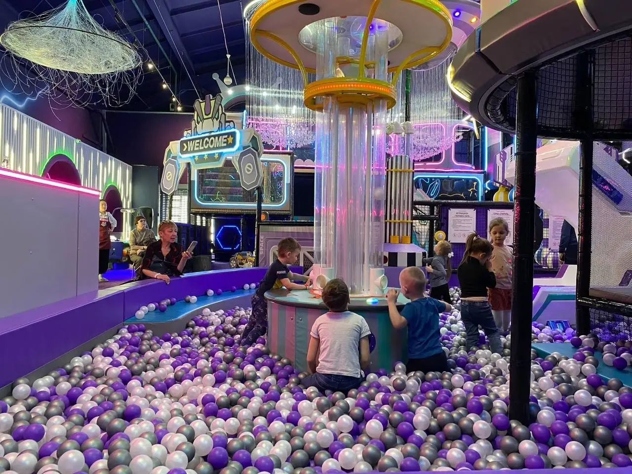 Фиолетовые и белые шарики в сухом бассейне, сухой фонтан с шариками и большой детский лабиринт в развлекательном центре для детей и большой детский лабиринт в развлекательном центре для детей.
