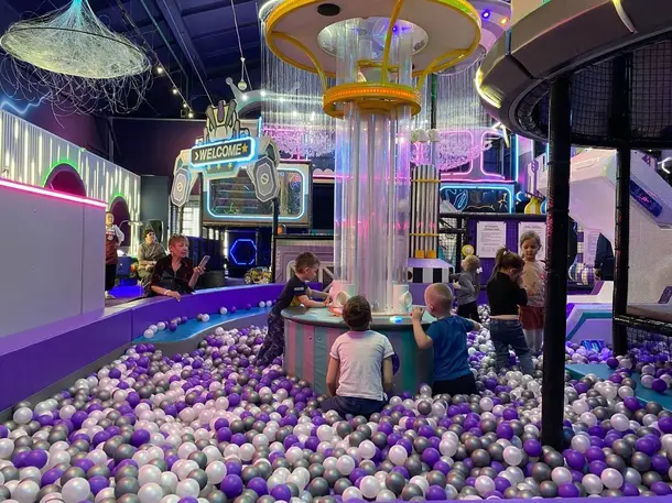 Фиолетовые и белые шарики в сухом бассейне, сухой фонтан с шариками и большой детский лабиринт в развлекательном центре для детей и большой детский лабиринт в развлекательном центре для детей.