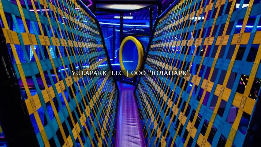 Вязанный мост с синими и оранжевым плетением или полосками который ведет к высокой горке в парке Движок.