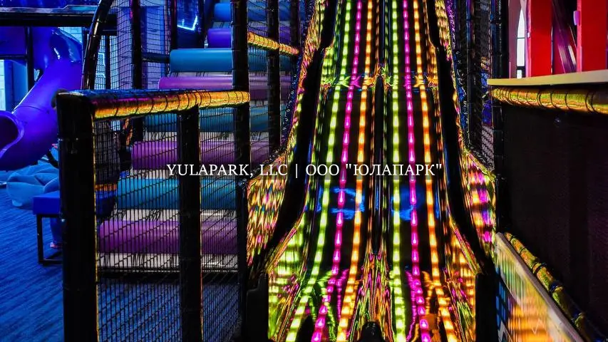 Черная пластиковая горка с неоновой анимированной подсветкой в виде дождика на фоне большого лабиринта в парке Движок.