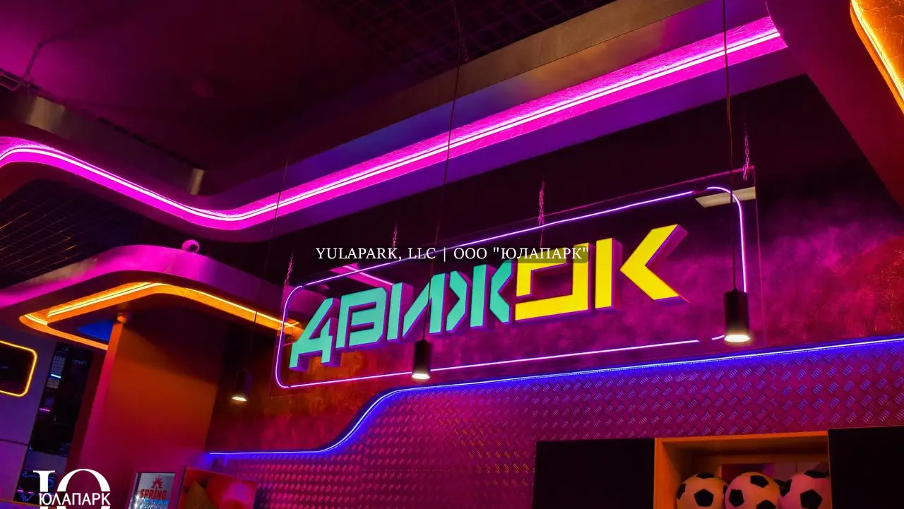 Вход и входная группа в детский активити-парк Движок в Омске с неоновой розовой, синей и желтой подсветками.