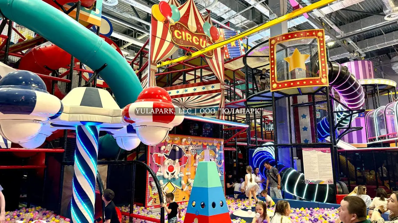Большая игровая зона в виде цирка для детей с большим сухим бассейном, различными каруселями, горками, скайрайдером и лабиринтами с неоновой подсветкой в детском развлекательном парке Флик-Фляк.