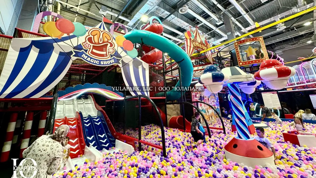 Большая игровая зона в виде цирка для детей с большим сухим бассейном, различными каруселями, горками, скайрайдером и лабиринтами с неоновой подсветкой в детском развлекательном парке Флик-Фляк.