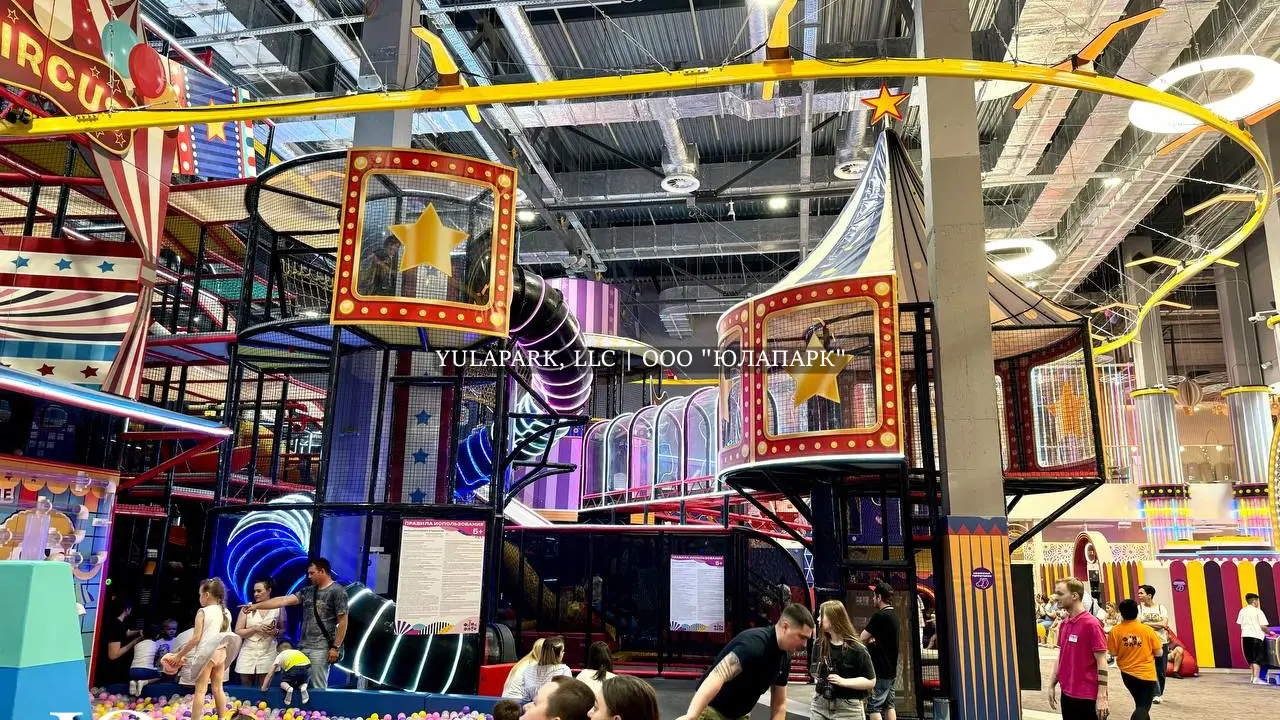 Большая игровая зона в виде цирка для детей с большим сухим бассейном, различными каруселями, горками, скайрайдером и лабиринтами с неоновой подсветкой в детском развлекательном парке Флик-Фляк.