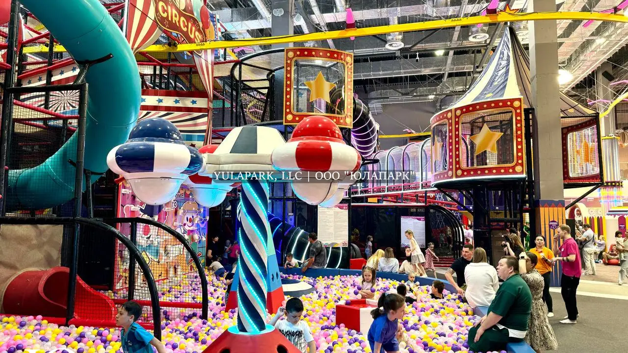 Большая игровая зона в виде цирка для детей с большим сухим бассейном, различными каруселями, горками и лабиринтами с неоновой подсветкой в детском развлекательном парке Флик-Фляк.