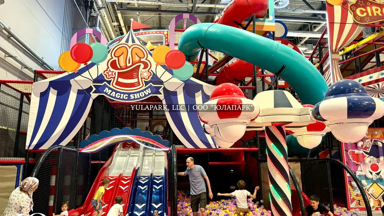 Большая игровая зона в виде цирка для детей с большим сухим бассейном, различными каруселями, горками, скайрайдером и лабиринтами с неоновой подсветкой в детском развлекательном парке Флик-Фляк.