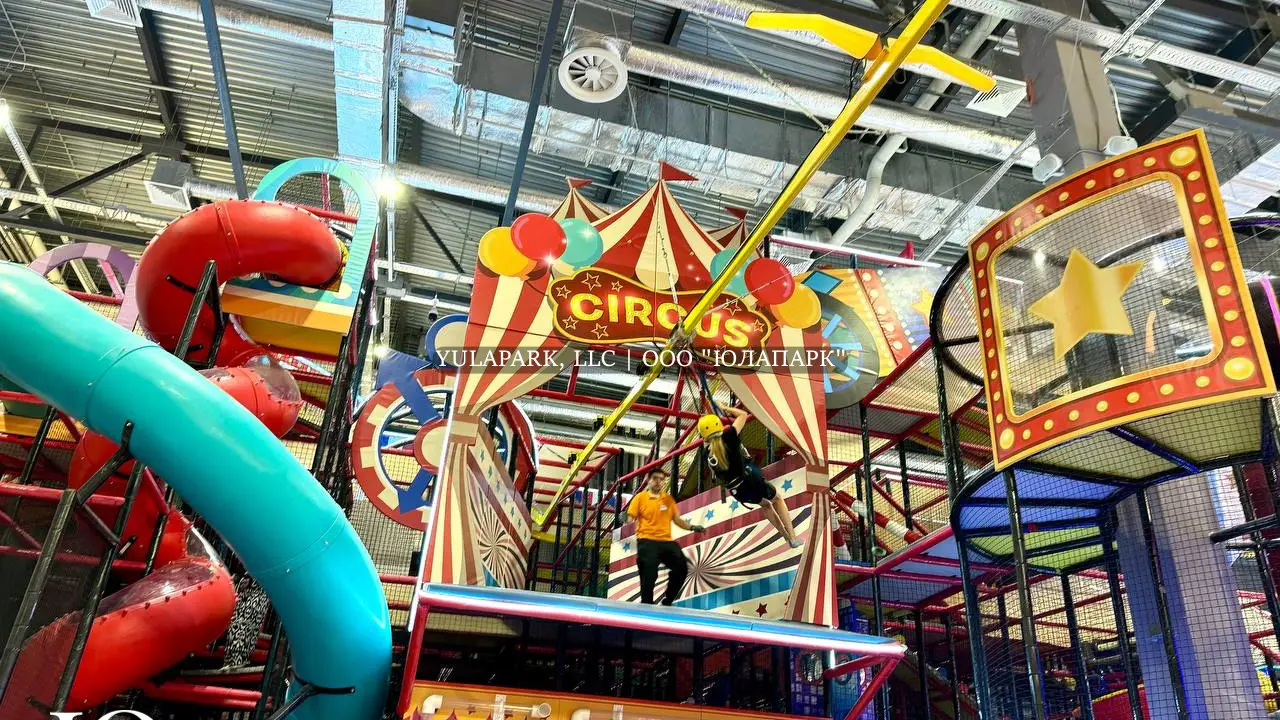 Большая игровая зона в виде цирка для детей с большим сухим бассейном, различными каруселями, горками, скайрайдером и лабиринтами с неоновой подсветкой в детском развлекательном парке Флик-Фляк.