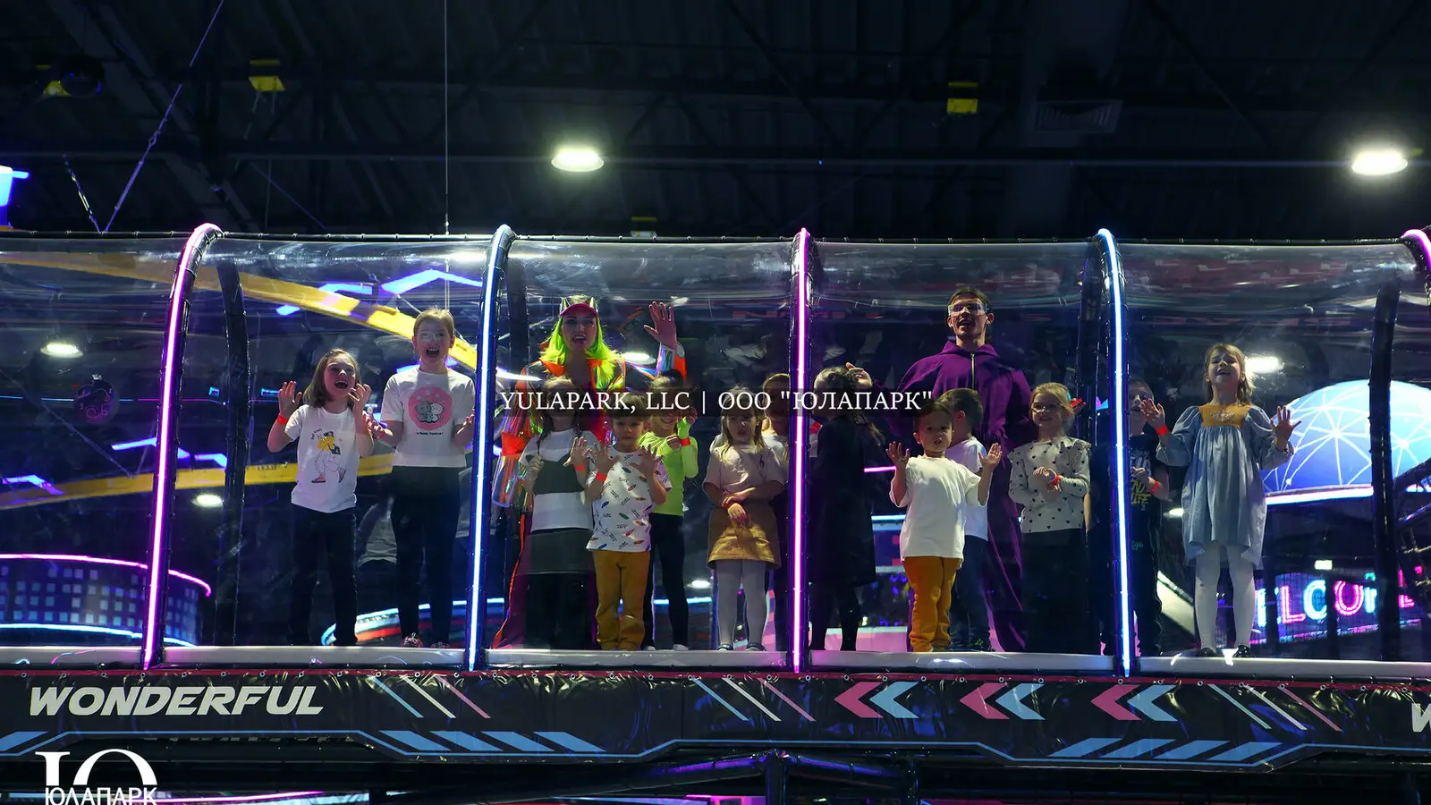 Glass, transparent bridge with illumination in the children's indoor park in the Shopping Center, in the family park, where joyful children stand.
