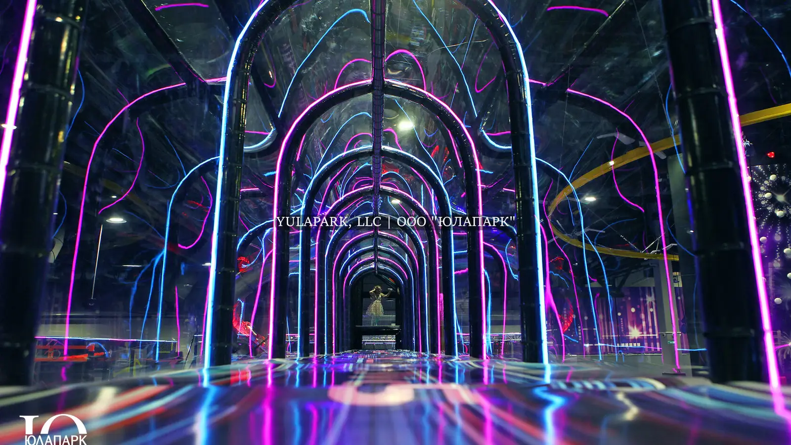 Glass, transparent bridge with neon lights in a children's amusement indoor park for the whole family.