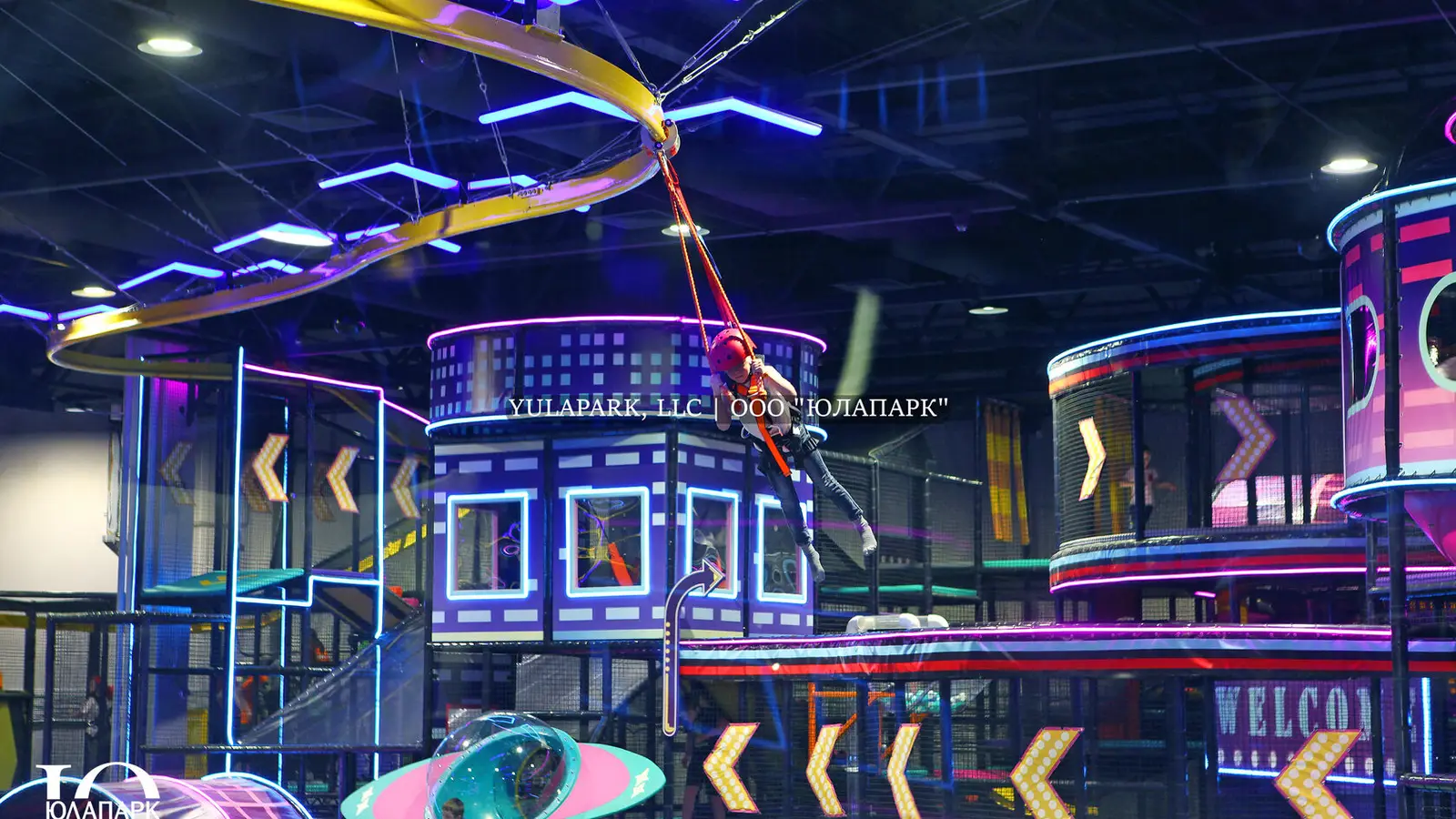 A children's playroom with a glowing skyrider, where a child flies over a park in the style of the city of the future and with a lot of lighting.
