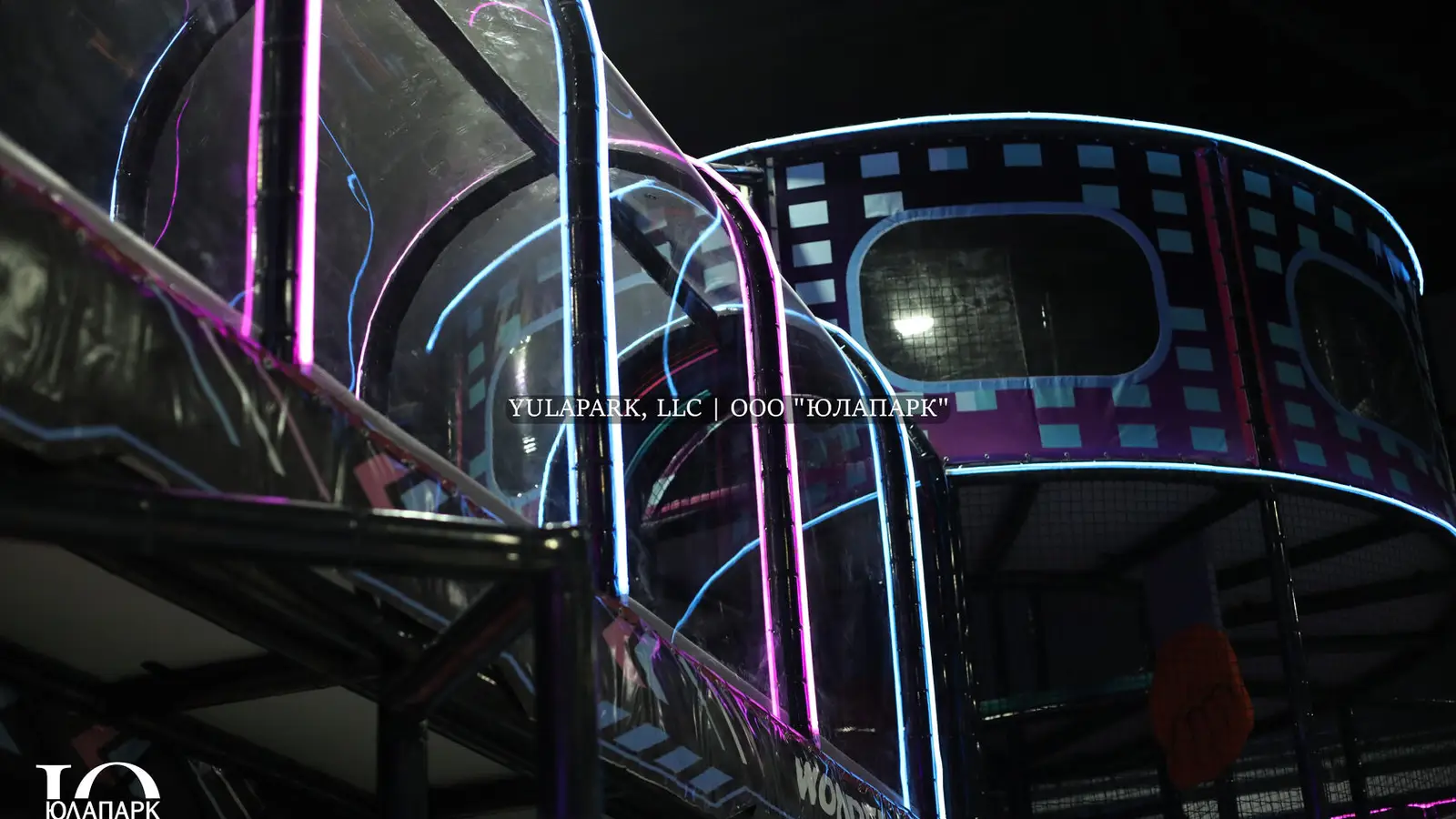Glass, transparent bridge with neon lights in a children's amusement indoor park for the whole family.