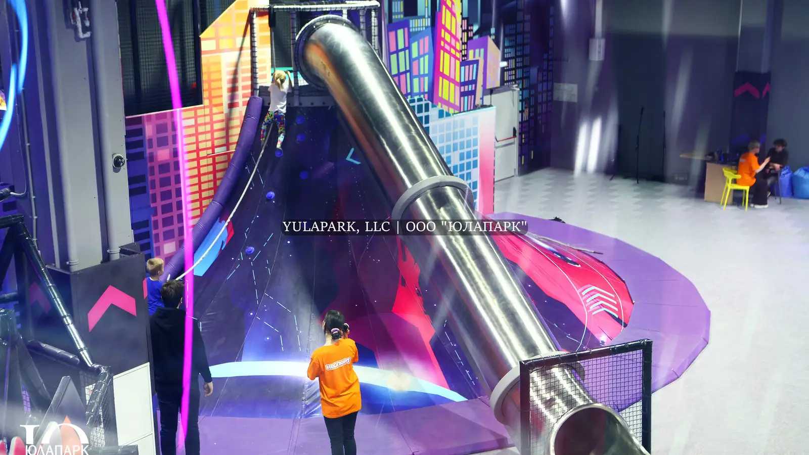 A huge volcano with a steel slide that kids climb in a play park, a family amusement park.