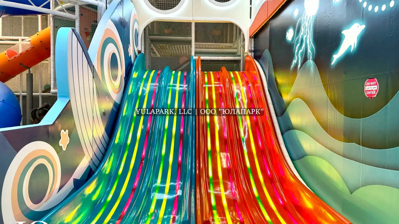 Игровая зона в детском парке с разноцветными светящимися анимированными горками и лабиринт в виде кораллов в Октопусе парке в Дубае