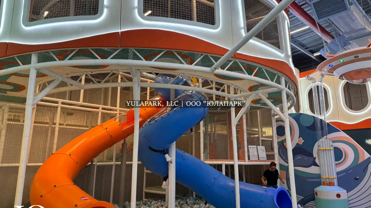 Разноцветные горки синего и оранжевого цвета в детском игровом центре в виде корралов и подводного мира, светящийся лабиринт с неоновой подсветкой в Дубае.