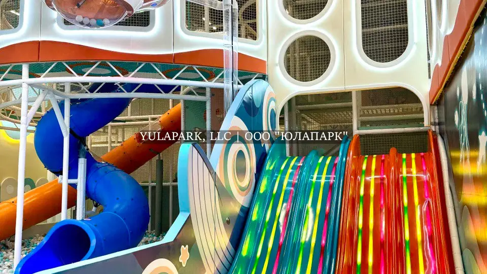 Игровая зона в детском парке с разноцветными светящимися анимированными горками и лабиринт в виде кораллов в Октопусе парке в Дубае