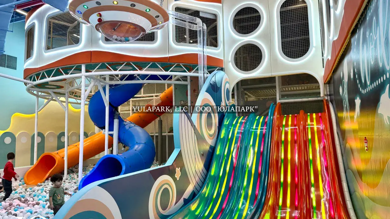 Игровая зона в детском парке с разноцветными светящимися анимированными горками и лабиринт в виде кораллов в Октопусе парке в Дубае