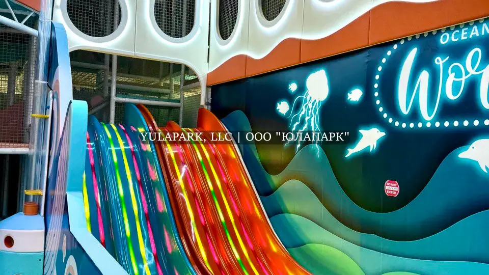 Игровая зона в детском парке с разноцветными светящимися анимированными горками и лабиринт в виде кораллов в Октопусе парке в Дубае