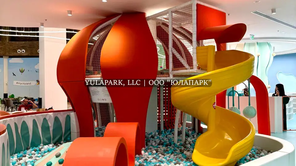 Входная зона в детском игровом, развлекательном парке в морской тематике с большим оранжевым осьминогом на входе. Большой осьминог в парке развлечений в виде горок и сухого бассейна